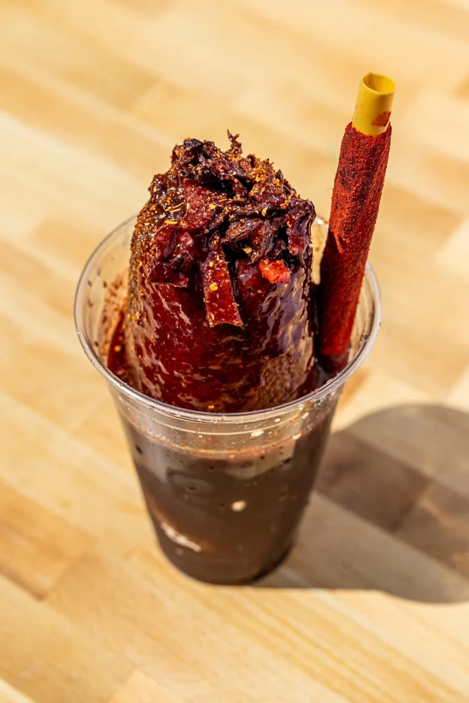 Tamarindo diablito raspado topped with chamoy, chili seasoning, and a tamarind candy stick.